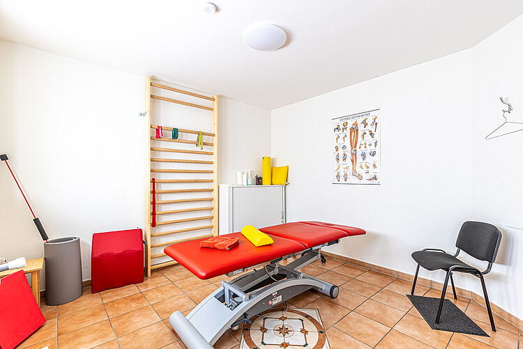 Raum mit Behandlungsliege, Sprossenwand und Trainingsgeräten