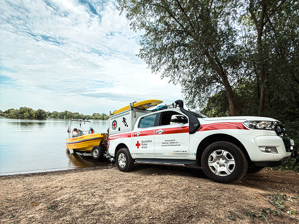Einsatzfahrzeug der DRK Wasserwacht zieht gelbes Rettungsboot ins Wasser