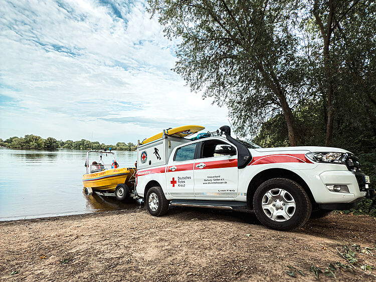 Einsatzfahrzeug der DRK Wasserwacht zieht gelbes Rettungsboot ins Wasser