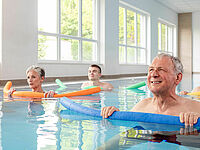 Teilnehmende bei der Wassergymnastik des DRK Mittelhessen mit Poolnudeln im Bewegungsbecken