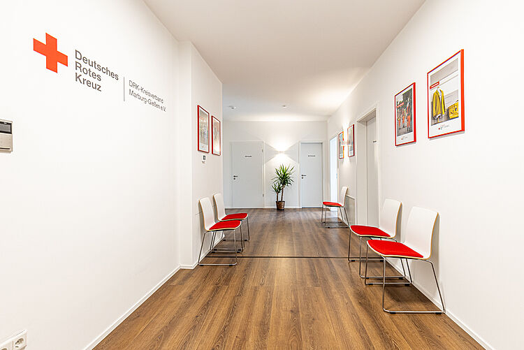 Flur mit roten Stühlen und DRK-Logo an der Wand