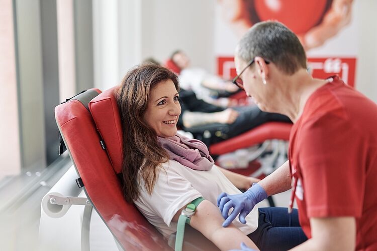 Gemeinsam Leben retten – Blutspende beim DRK Mittelhessen Lächelnde Frau spendet Blut, betreut von DRK-Mitarbeiterin