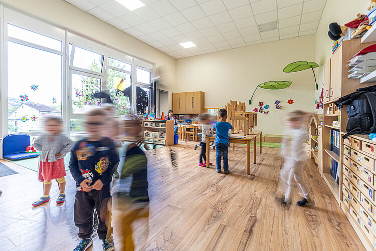 Kinder spielen im hellen Gruppenraum mit Bastel- und Bauecke