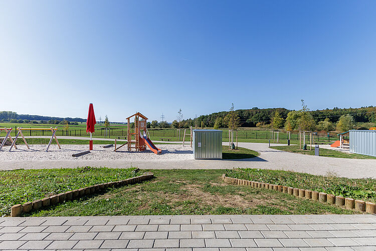 Spielplatz mit Rutsche, Sandfläche und Blick über Wiesen und Felder