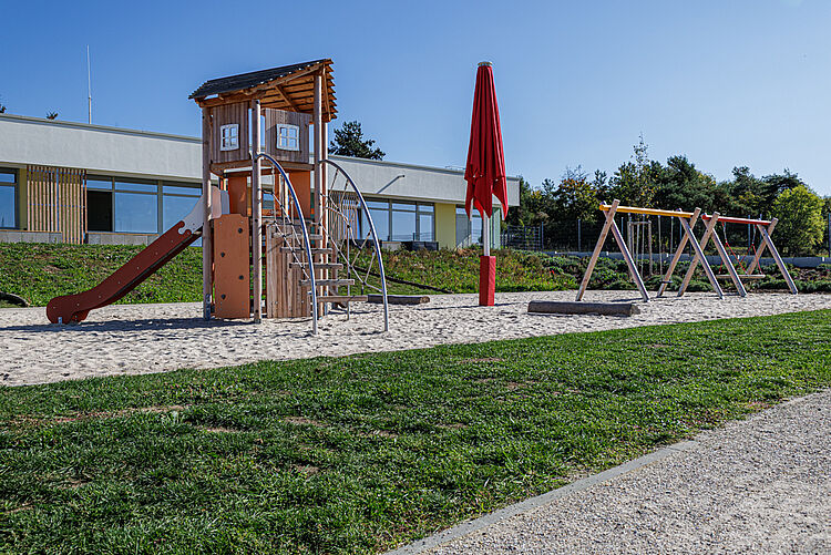 Spielturm mit Rutsche und mehrere Schaukeln auf dem Außengelände der Kita