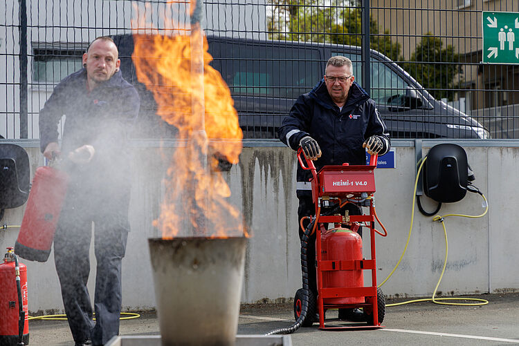 Teilnehmer löschen kontrolliertes Feuer mit Löschgerät beim Brandschutzhelfer Lehrgang
