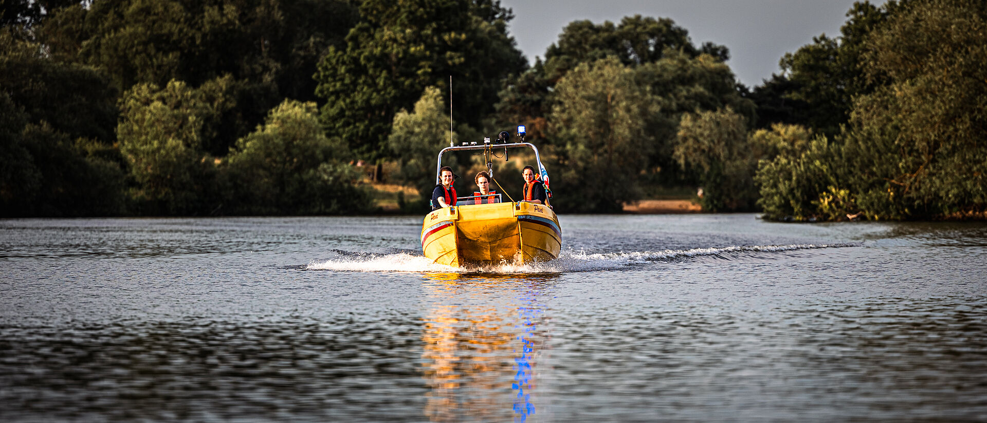 Mitglieder der DRK Wasserwacht auf einem gelben Rettungsboot bei einer Übung auf dem See