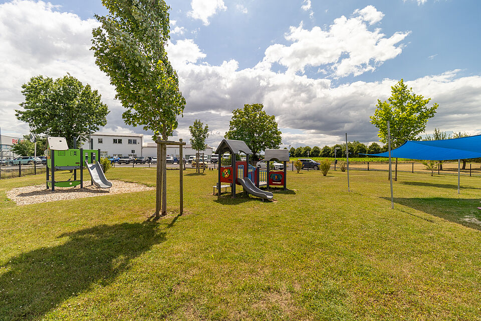 Spielplatz mit Rutsche, Häuschen und Sonnenschutz im Garten der DRK-Kita Heuchelheim