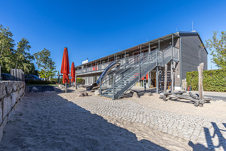 DRK-Kita „Henrys kleine Forscher“ in Staufenberg-Daubringen – Moderne Kindertagesstätte mit Spielbereich Außenansicht der DRK-Kita „Henrys kleine Forscher“ in Staufenberg-Daubringen mit Spielplatz, Rutsche und Sonnenschirmen