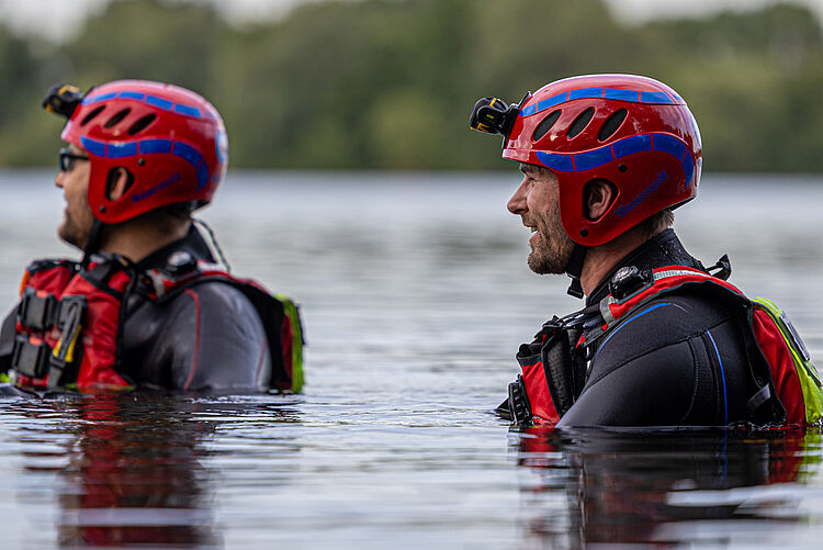 Zwei Einsatzkräfte / Rettungsschwimmer der DRK Wasserwacht mit Helmen im Wasser