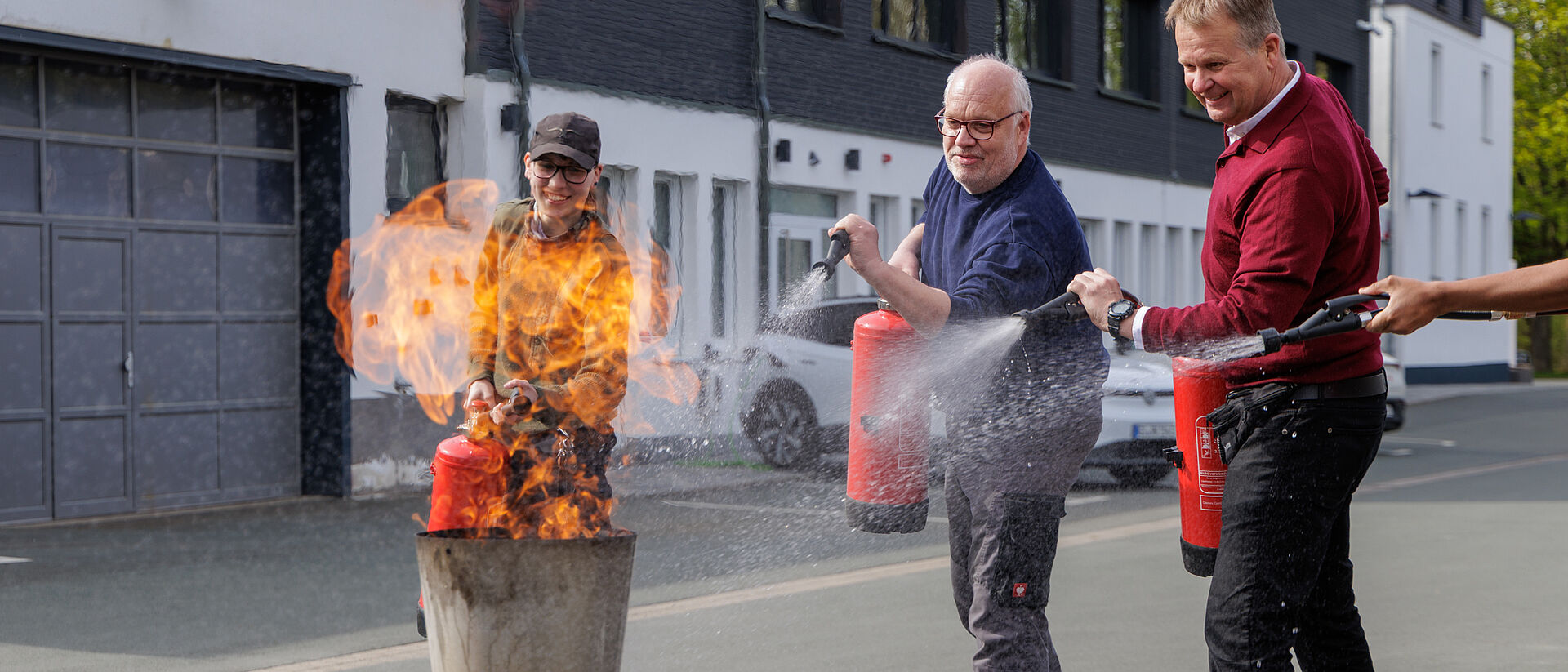 Mehrere Teilnehmer löschen gemeinsam ein Feuer mit Feuerlöschern bei Übung