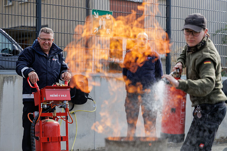 Teilnehmer löscht Brandherd mit Feuerlöscher unter Anleitung eines Ausbilders