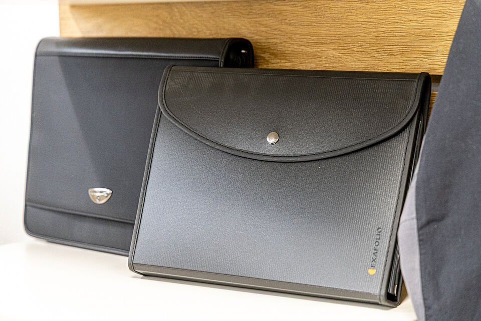 Schwarze Aktenmappen im DRK Kleiderladen Marburg