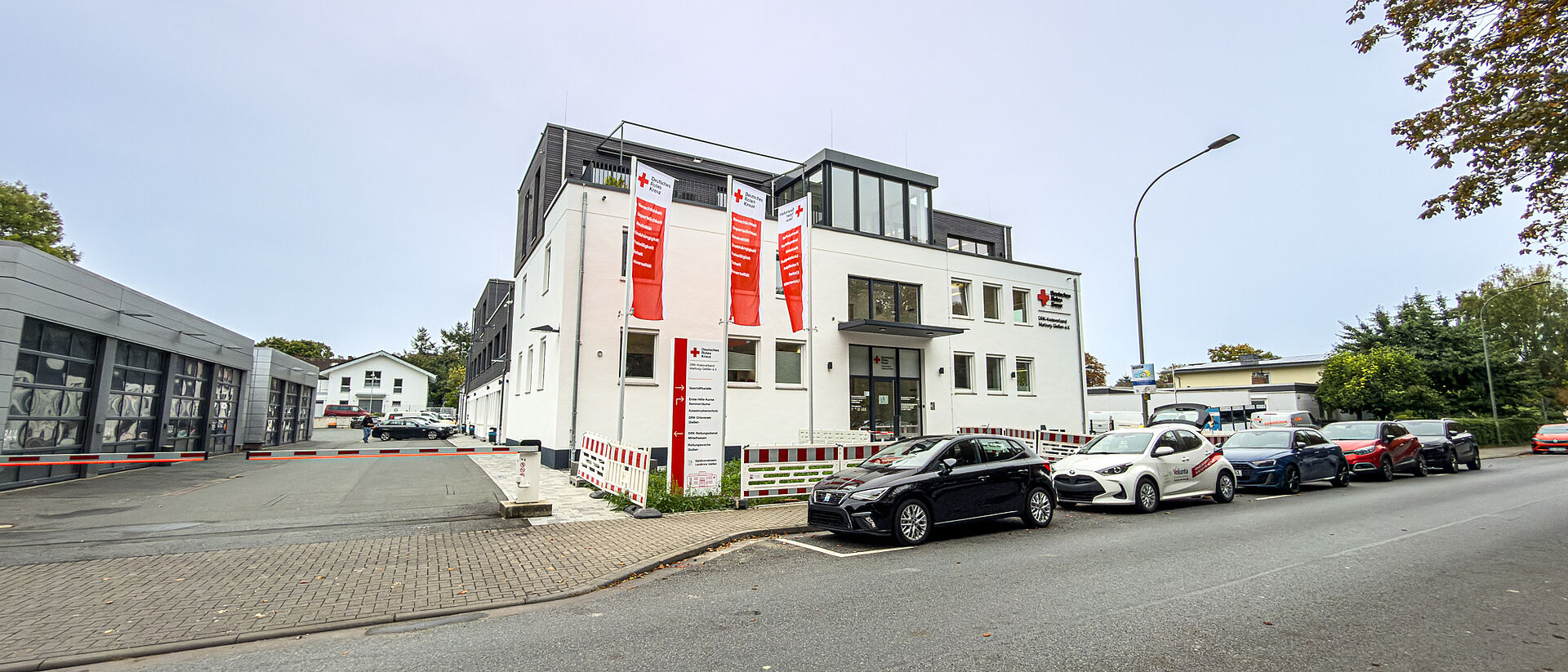 DRK Kreisverband Marburg-Gießen – Verwaltungs- und Kursstandort in der Eichgärtenallee Gebäude des DRK Kreisverbands Marburg-Gießen in der Eichgärtenallee mit DRK-Fahnen und geparkten Einsatzfahrzeugen