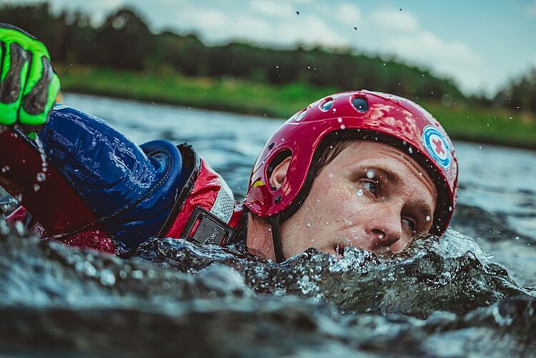 DRK Rettungsschwimmer mit Helm und Neoprenanzug bei einer Wasserrettungsübung im Freiwasser