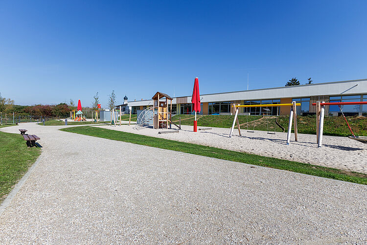 Weitläufiges Außengelände mit Spielturm, Schaukeln und Kita-Gebäude