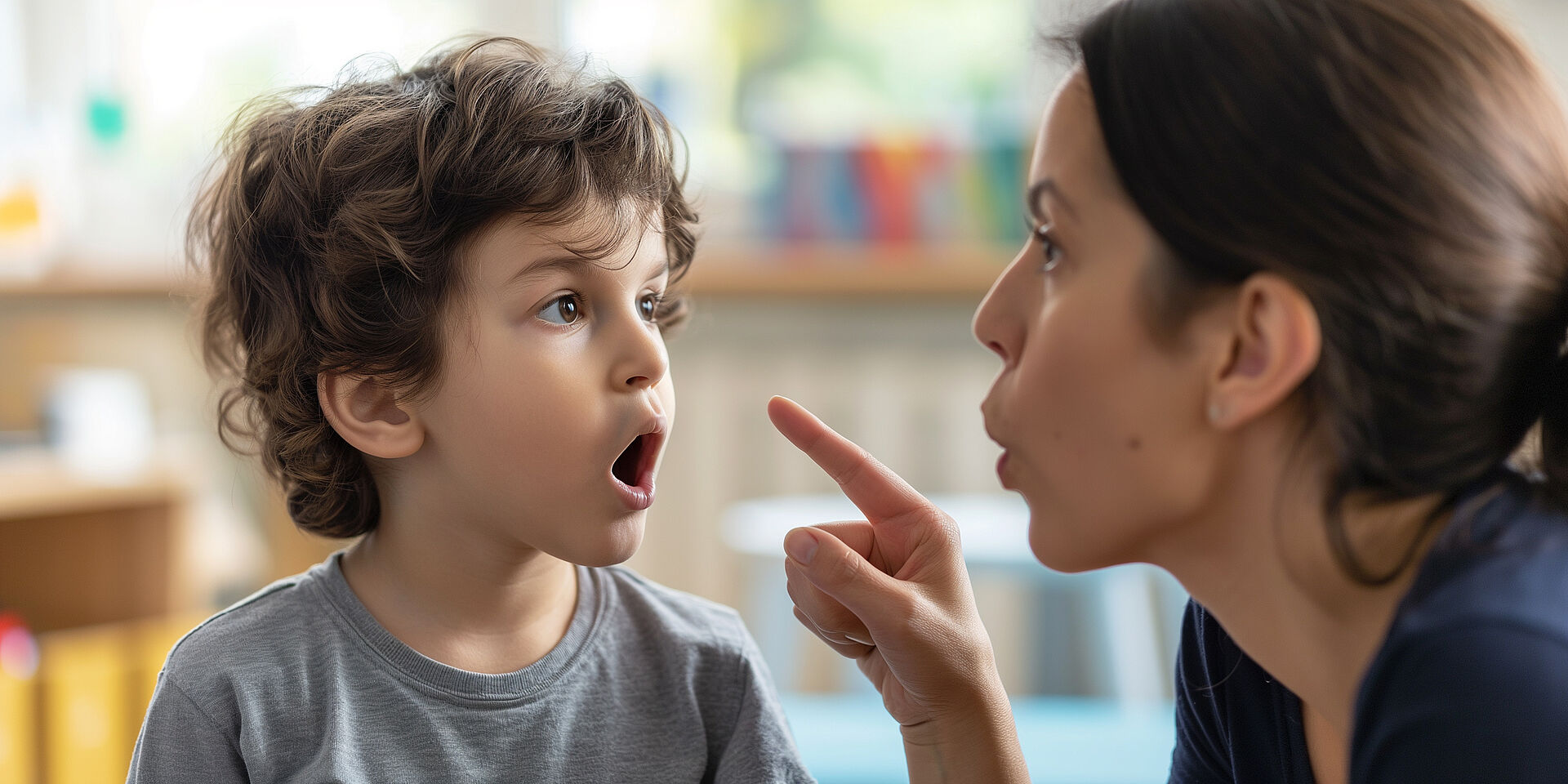 Logopädie für Kinder – Aussprachetraining mit der Sprachtherapeutin Junge wiederholt Laute unter Anleitung einer Logopädin