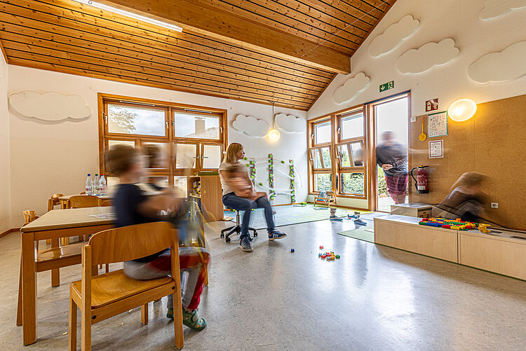 Kinder spielen im hellen Gruppenraum mit Wolken-Deko in der DRK-Kita Kunterbunt