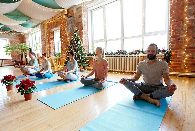 Gruppe beim meditativem Yoga in weihnachtlich geschmücktem Raum