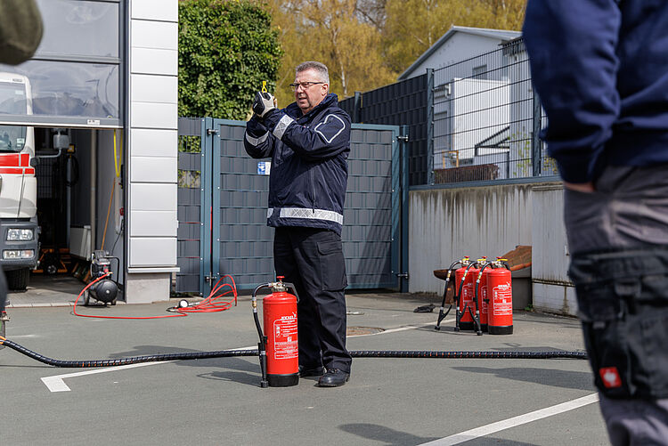 Ausbilder erklärt die Handhabung eines Feuerlöschers während einer praktischen Brandschutzübung