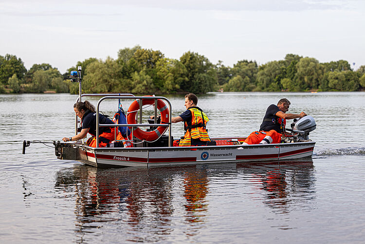 DRK Wasserwacht-Team steuert Aluminiumboot mit Rettungsringen über den See