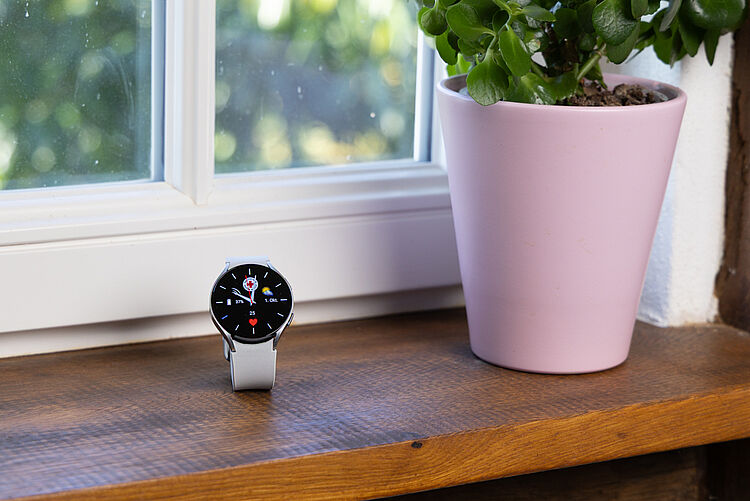 Notrufuhr mit DRK-Logo steht auf einer Fensterbank neben Blumentopf