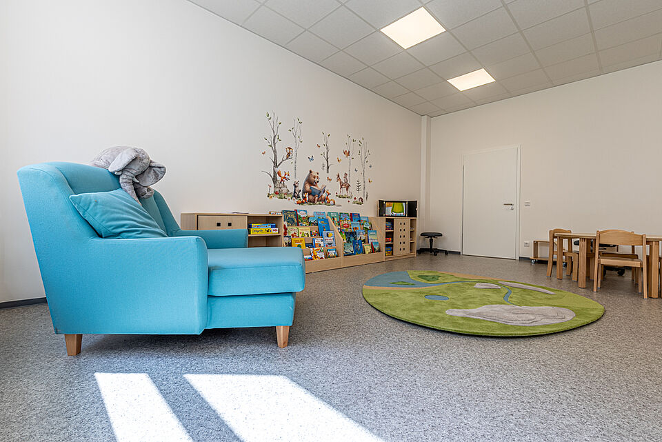 Heller Gruppenraum mit blauer Sitzlounge und Bücherregalen in der DRK-Kita „Henrys Märchenwelt“