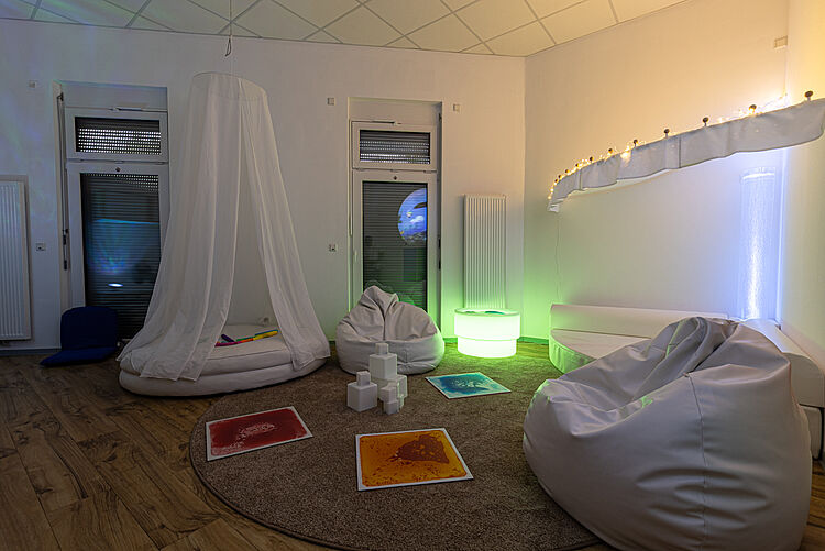 Ruhig gestalteter Entspannungsraum mit Sitzsäcken, Lichtspielen und Projektionen