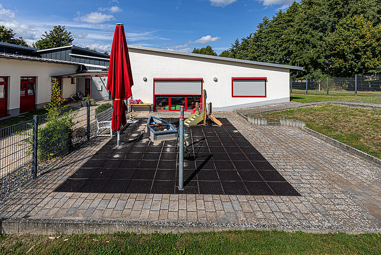Abgetrennter Spielbereich mit Sandkasten und Sonnenschirm im Außenbereich