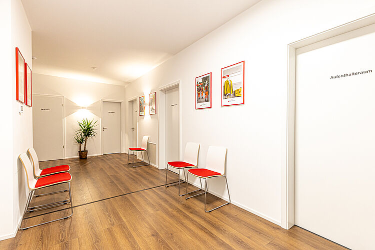 Flur mit Sitzgelegenheiten, Pflanzen und Beschilderung der Therapieräume