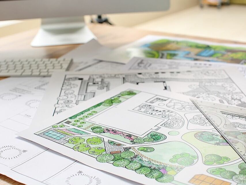 Landschaftsplan mit Bepflanzungsskizze und Gartenentwurf auf einem Schreibtisch