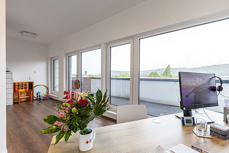 Schreibtisch mit Computer und Blumenstrauß in der DRK-Therapiepraxis Marburg-Cappel