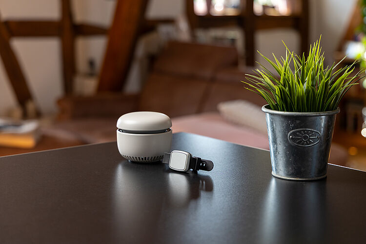 Hausnotrufgerät mit Notrufarmband auf einem Tisch in gemütlicher Wohnumgebung