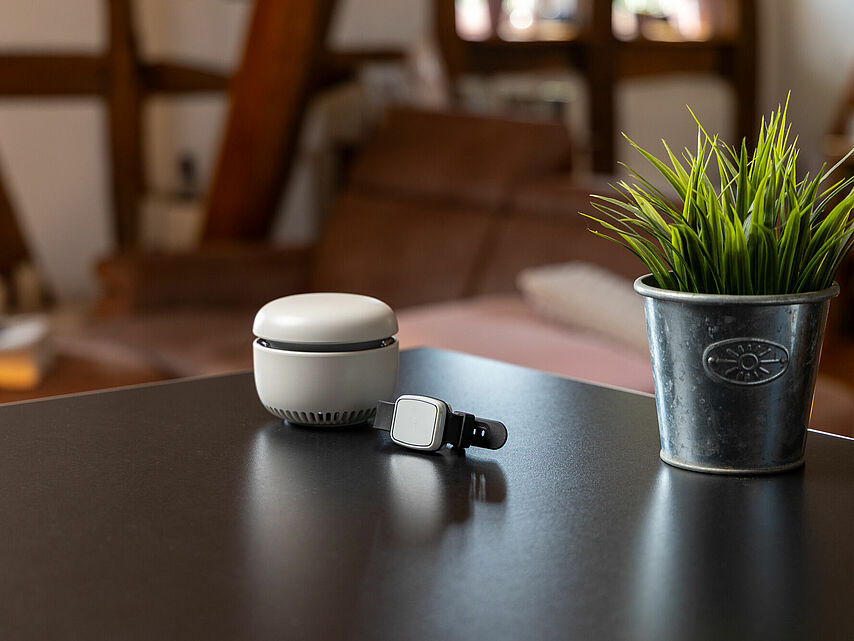 Hausnotrufgerät mit Notrufarmband auf einem Tisch in gemütlicher Wohnumgebung