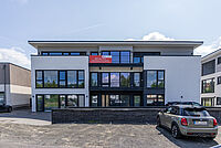 Modernes Gebäude der neuen DRK Logopädiepraxis in Marburg-Cappel mit Banner „Neu ab 1. Juli“