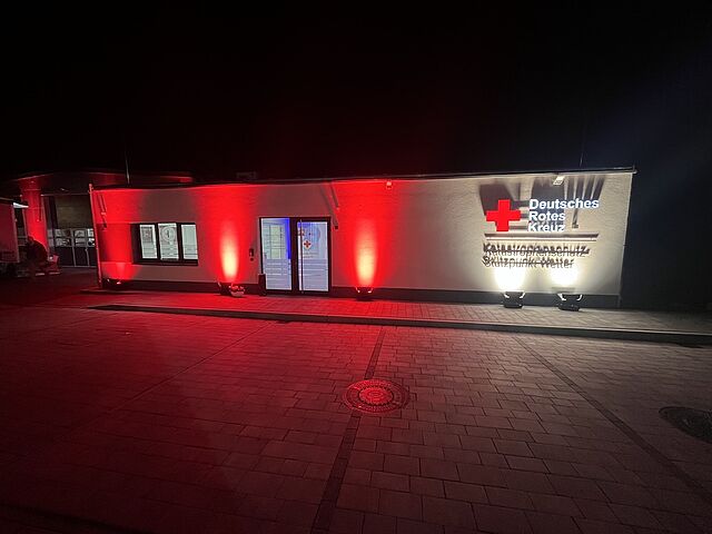 DRK-Stützpunkt Wetter bei Nacht mit rot beleuchtetem Gebäude und DRK-Logo
