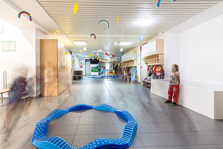 Kinder bewegen sich durch den hellen Flur der Kita „Rabennest“ mit bunten Dekorationen und Spielgeräten