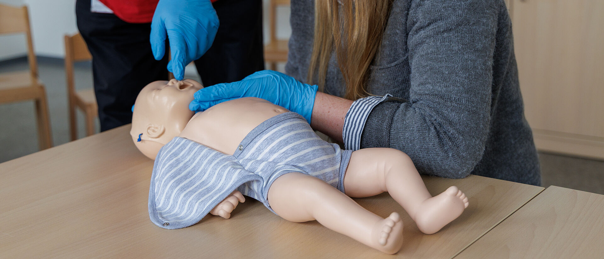 Teilnehmer prüfen Atmung einer Säuglingspuppe im Erste Hilfe am Kind Kurs