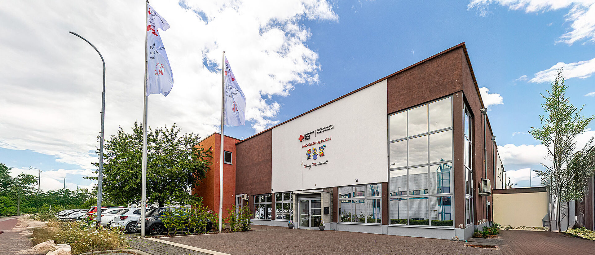 Außenansicht der DRK-Kindertagesstätte „Henrys kleine Forscher“ in Staufenberg-Daubringen mit Fahnen und Eingangsbereich