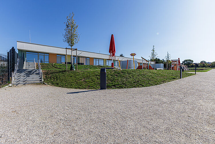 Außenansicht der Kita Pohlheim Watzenborn-Steinberg mit Spielplatz und Grünanlage