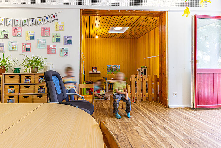 Kinder spielen im Gruppenraum der DRK-Kita „Rabennest“ mit Holzecke und Geburtstagswand