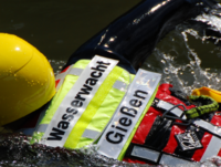 Mitglied der Wasserwacht Gießen mit Helm und Rettungsweste schwimmt im Einsatz