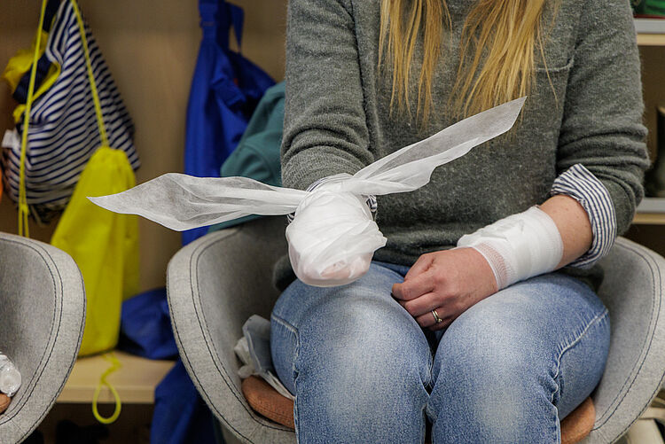 Teilnehmerin mit verbundenem Arm übt Verbandtechnik im Erste Hilfe Kurs für Kinder