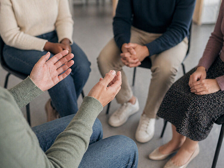 Menschen sitzen im Kreis und sprechen in einer Gruppentherapie zur Suchtbewältigung