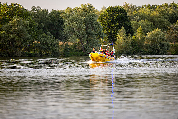 Gelbes Rettungsboot der DRK Wasserwacht fährt über den See