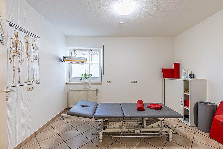 Raum mit grauer Therapieliege und Wärmestrahler in der DRK-Therapiepraxis