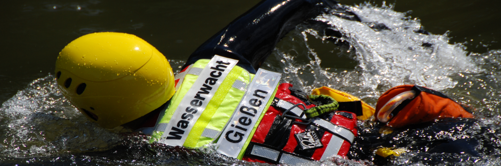 Mitglied der Wasserwacht Gießen mit Helm und Rettungsweste schwimmt im Einsatz